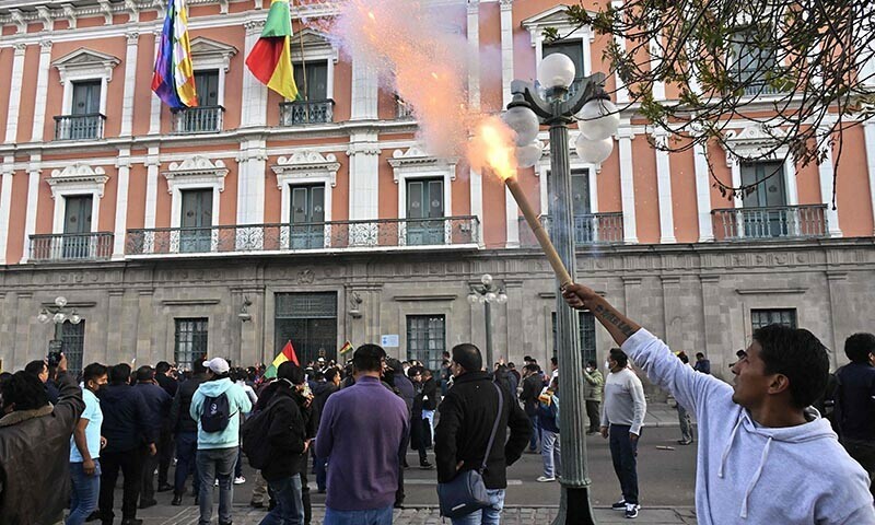 A supporter of Bolivian President Luis Arce fires a bengal outside Quemado Palace at Plaza Murillo in La Paz on June 26. — AFP